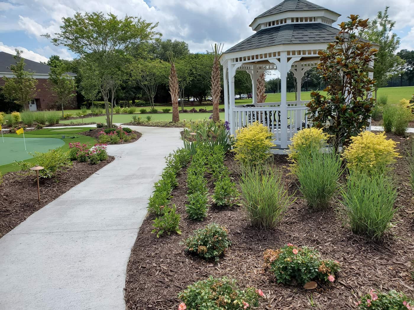 A maintained garden walk beside a gazebo and putting green